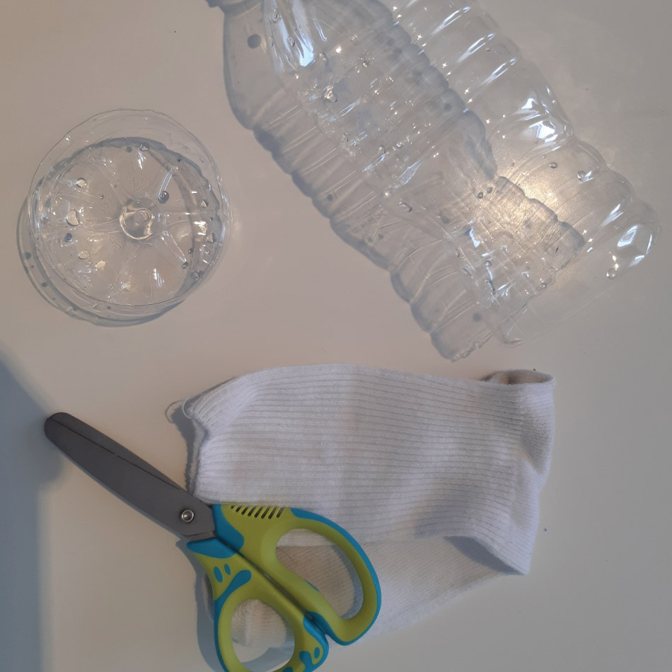 Matériel pour l'activité, dont une paire de ciseaux, une chaussette et une bouteille de plastique vide.