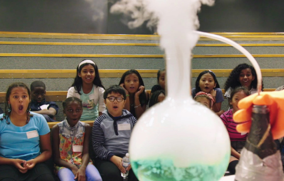 Des élèves s'émerveillent devant un ballon en verre d'où sort de la fumée.