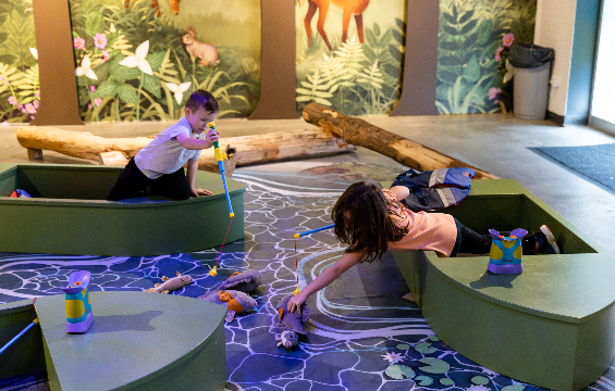 Deux enfants assis dans deux bateaux séparés attrapaient des poissons jouets avec une canne à pêche.