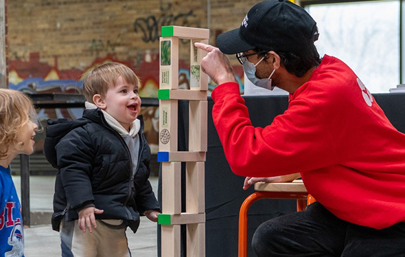 Un homme et deux enfants jouent au Jenga.
