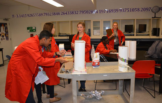 Des élèves de l'école des sciences en sarrau rouge travaillent à un projet.