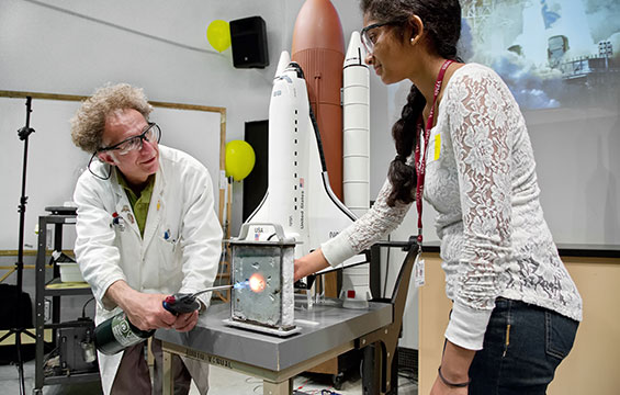 Un éducateur du Centre des sciences fait la démonstration d'un chalumeau allumé devant une enseignante.