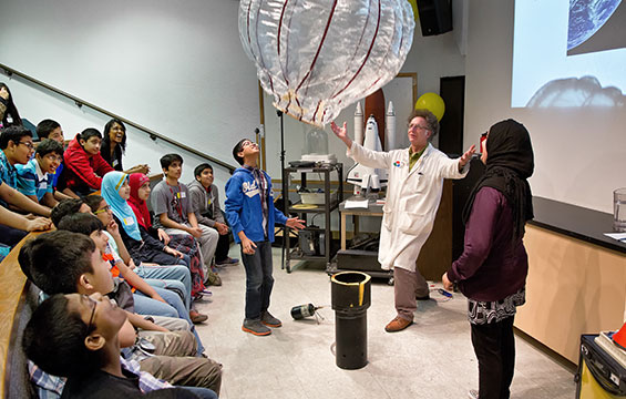 A class of students watches a Science Centre educator demonstrate with a large balloon.