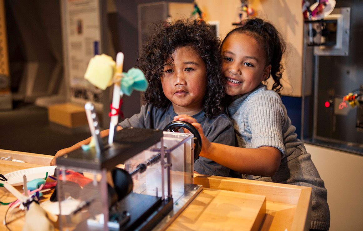 Deux jeunes enfants jouent avec une sculpture cinétique.