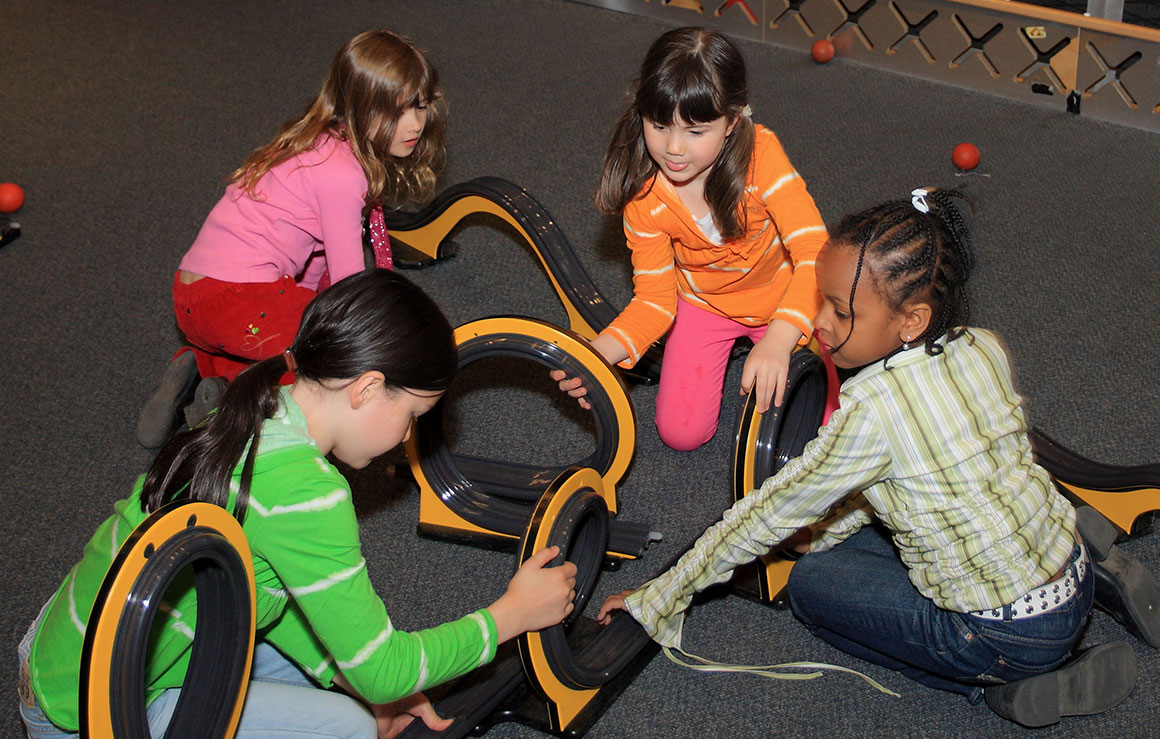 Quatre filles assemblent des pistes de montagnes russes.