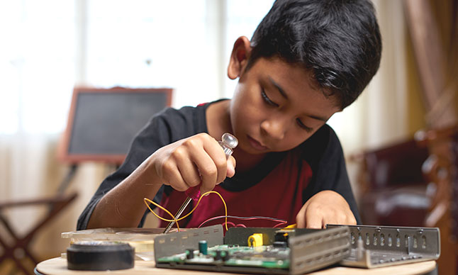 Un garçon se sert d'un jeu d'outils électroniques.