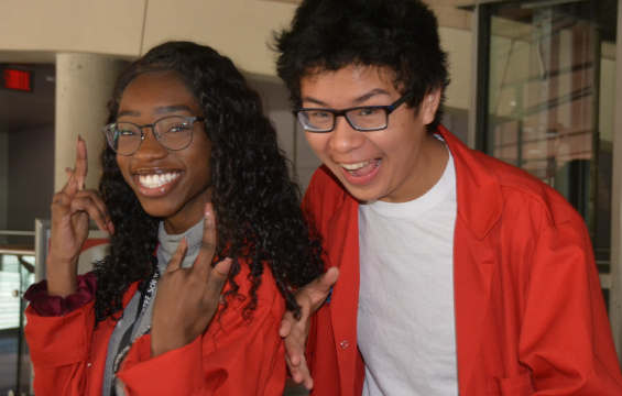 Deus élèves de leur sarrau rouge de l'École des sciences prennent la pose en souriant.