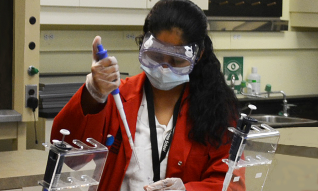 Une élève de l'École des sciences pipette un liquide dans un tube à essai.