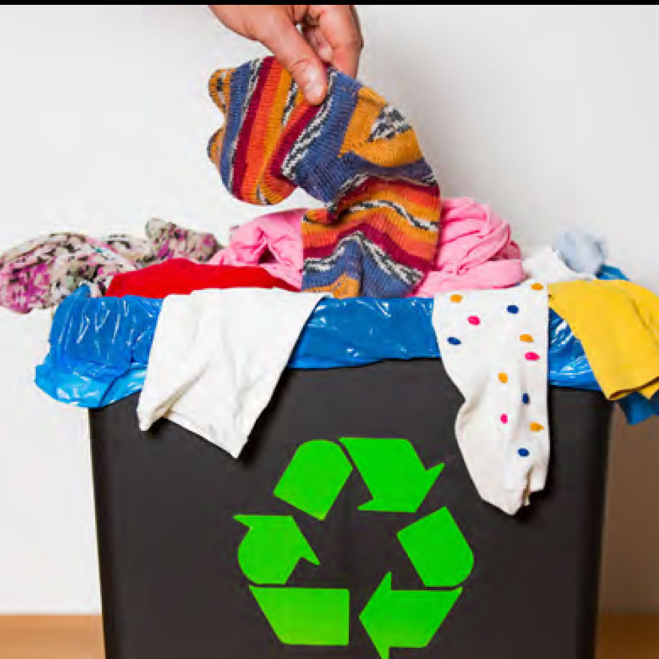 Une main déposant du tissu dans un bac de recyclage.