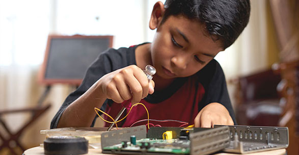 Un enfant expérimente sur des composantes électronique.