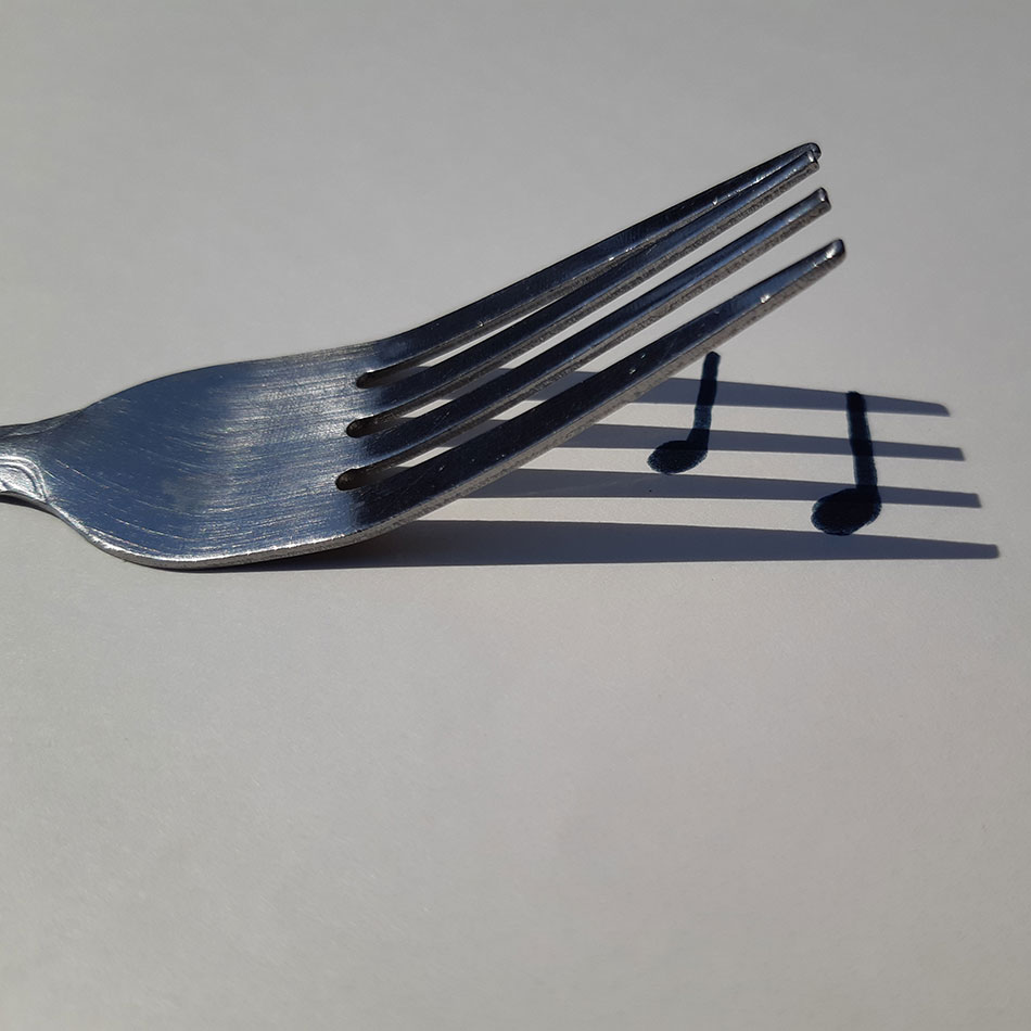 Une fourchette projette une ombre sur laquelle on a dessiné des notes de musique.