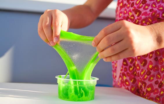 Des mains d'enfant étirant de la glu verte.