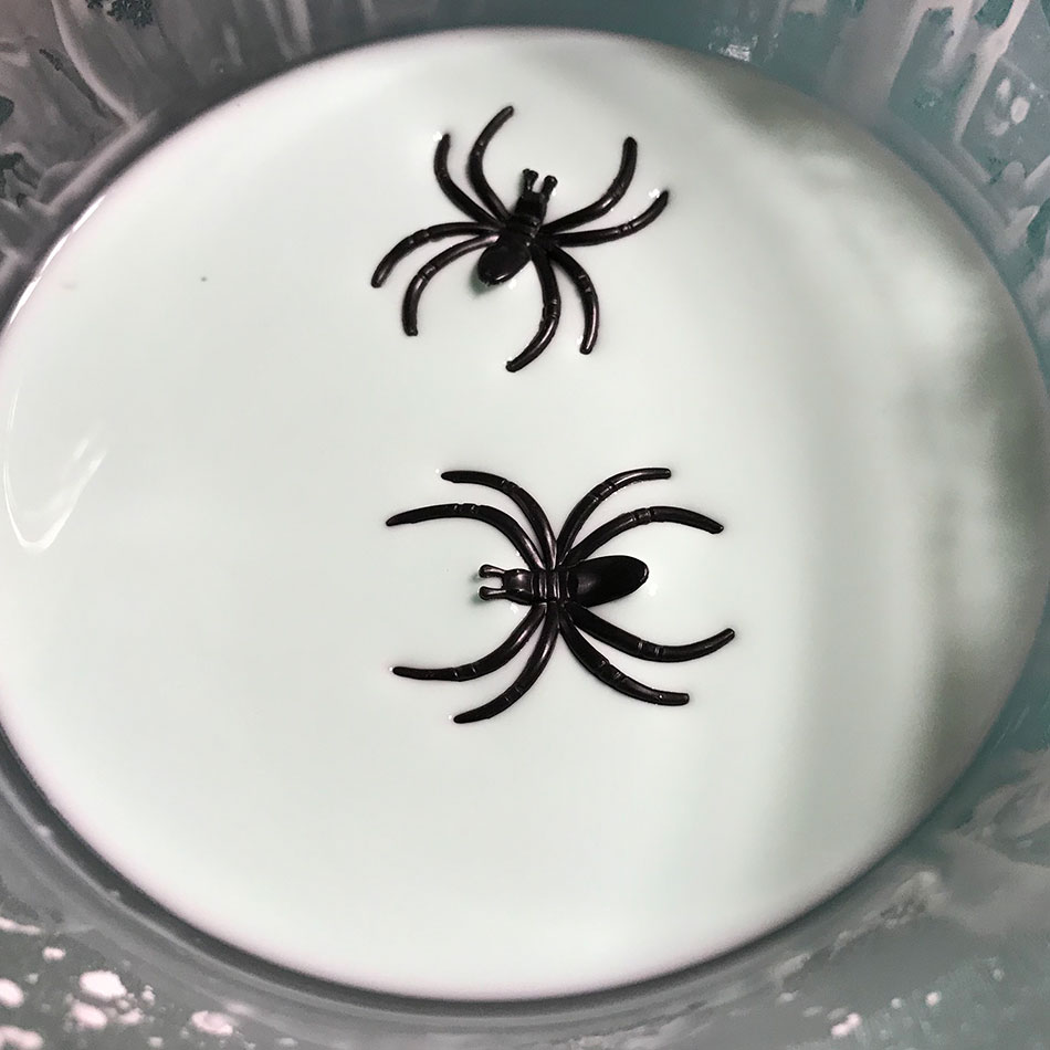 Deux araignées en plastique flottant sur un bol d'oobleck blanc.