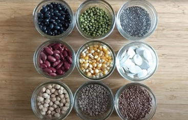Overhead photo of nine glass jars containing different seeds