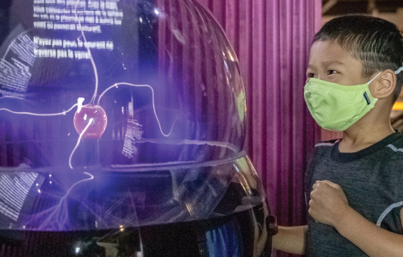 Un enfant portant un masque regarde une boule de plasma.