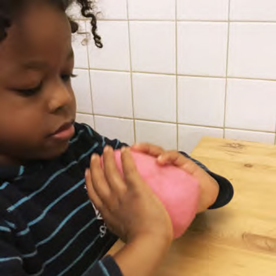 Un enfant pétris une boule de pâte à modeler maison.