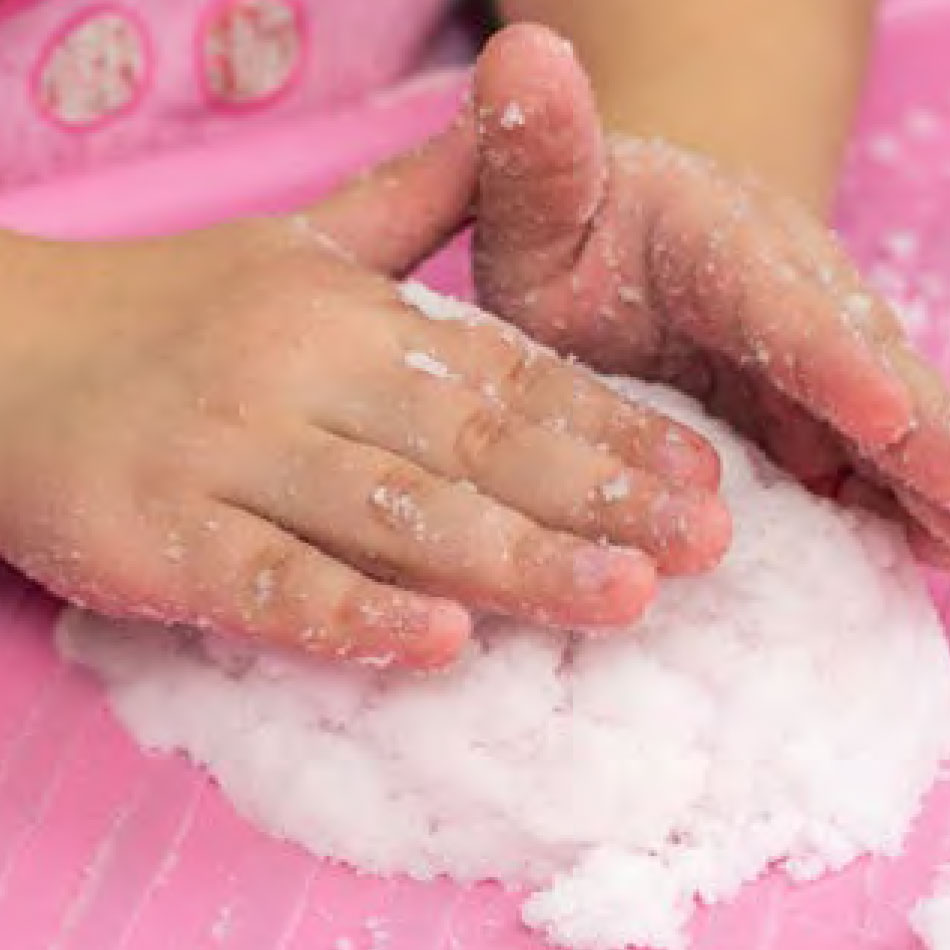 Gros plan de petites mains pressant sur la neige artificielle maison.