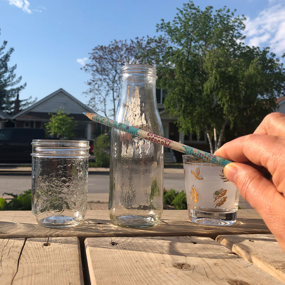 Un crayon butte contre des contenants en verre transparent.