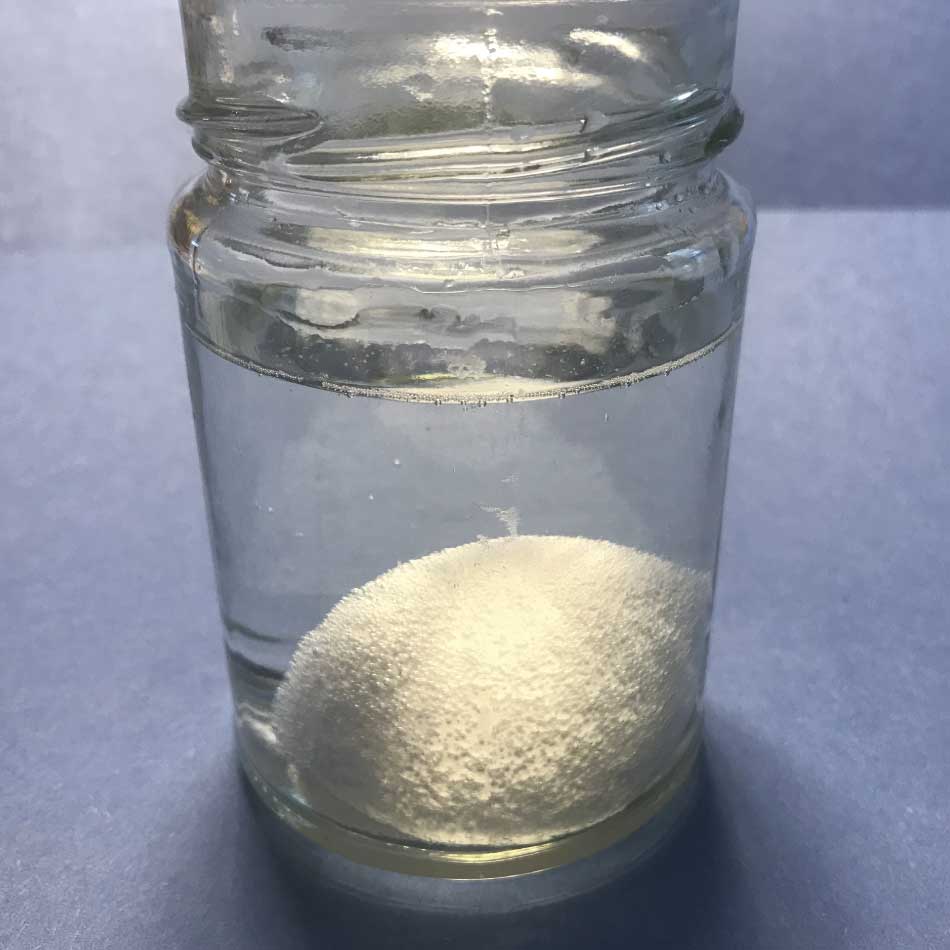 Un bocal contenant un oeuf submergé dans un liquide incolore. De petites bulles couvrent la surface de l'oeuf.