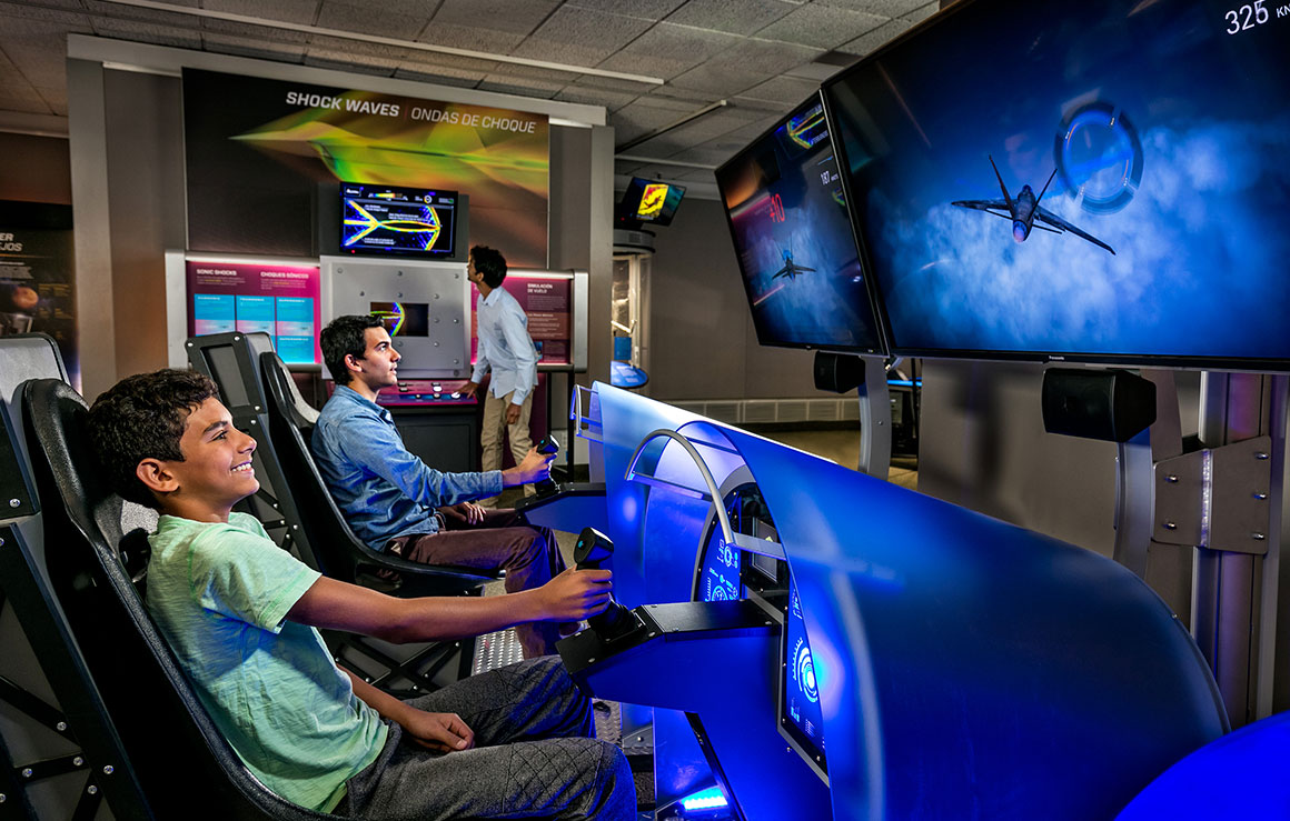 Un homme et un garçon assis dans des capsules immersives de simulateur de vol.