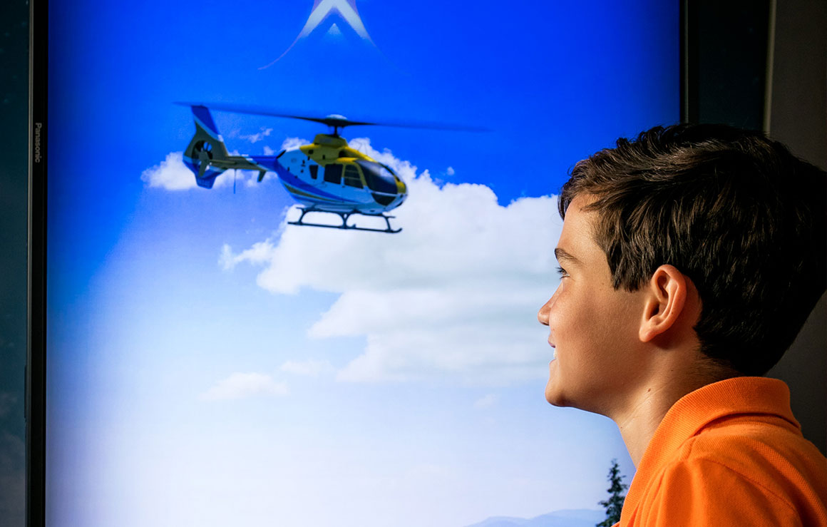 Un garçon regarde un hélicoptère sur un écran.