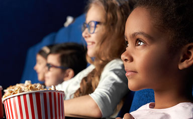 Des enfants regardant un film en mangeant du maïs soufflé.