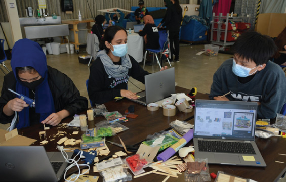Plusieurs élèves s'affairent à des projets de conception et d'ingénierie devant des portables, des outils et des matériaux hétéroclites.