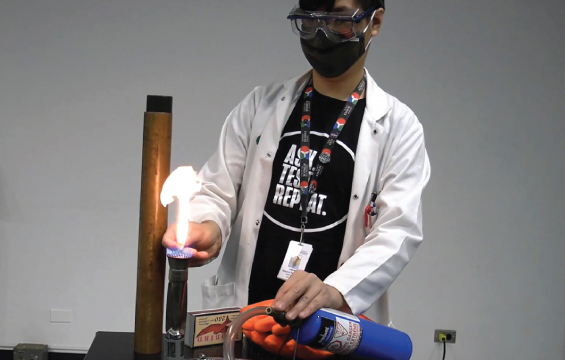 Un éducateur portant des lunettes de protection et un masque allume un brûleur.