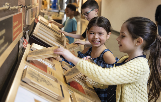 En souriant, de jeunes élèves soulèvent les panneaux en bois d’un module afin d’en lire l’information cachée.