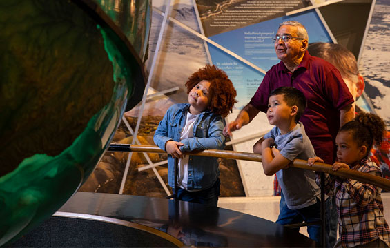 Un groupe de gens examine l'énorme globe terrestre du Hall de la Terre vivante.