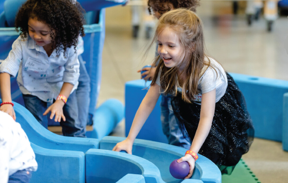 Deux enfants jouent avec des balles dans la structure Imagination Station.