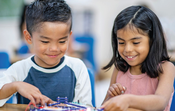 Two school children working with electronics and STEM materials in a workshop.