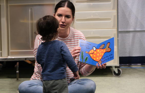Une femme lit un livre à un bambin.