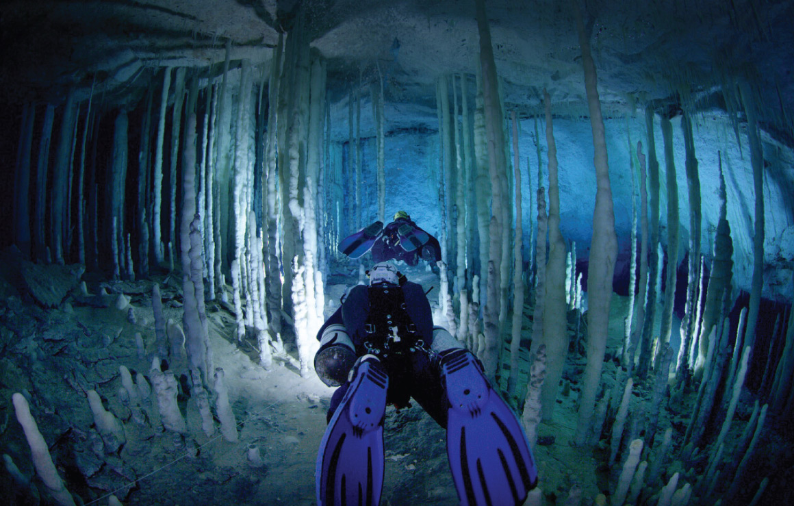 Deux personnes font de la plongée dans une grotte sous-marine.