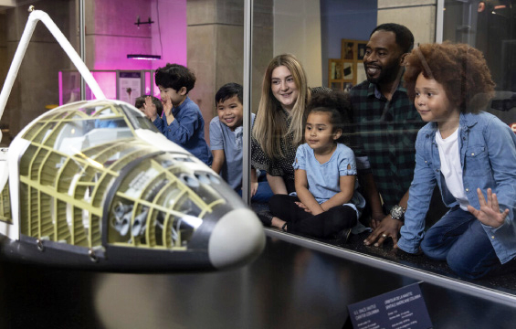 Deux adultes et plusieurs enfants admirent une maquette de la navette spatiale.