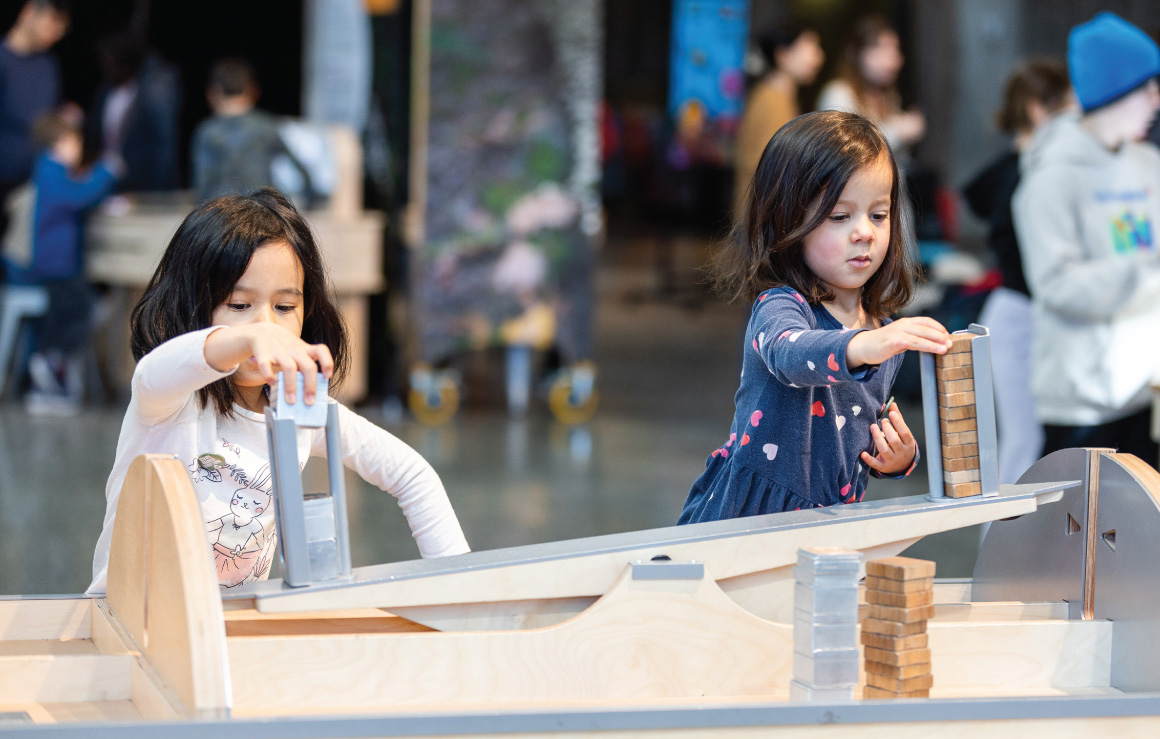 Deux enfants manipulent un des modules de l'exposition Notre Quête climatique.