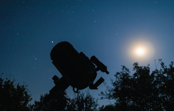Silhouette d'un télescope dans une nuit étoilée.