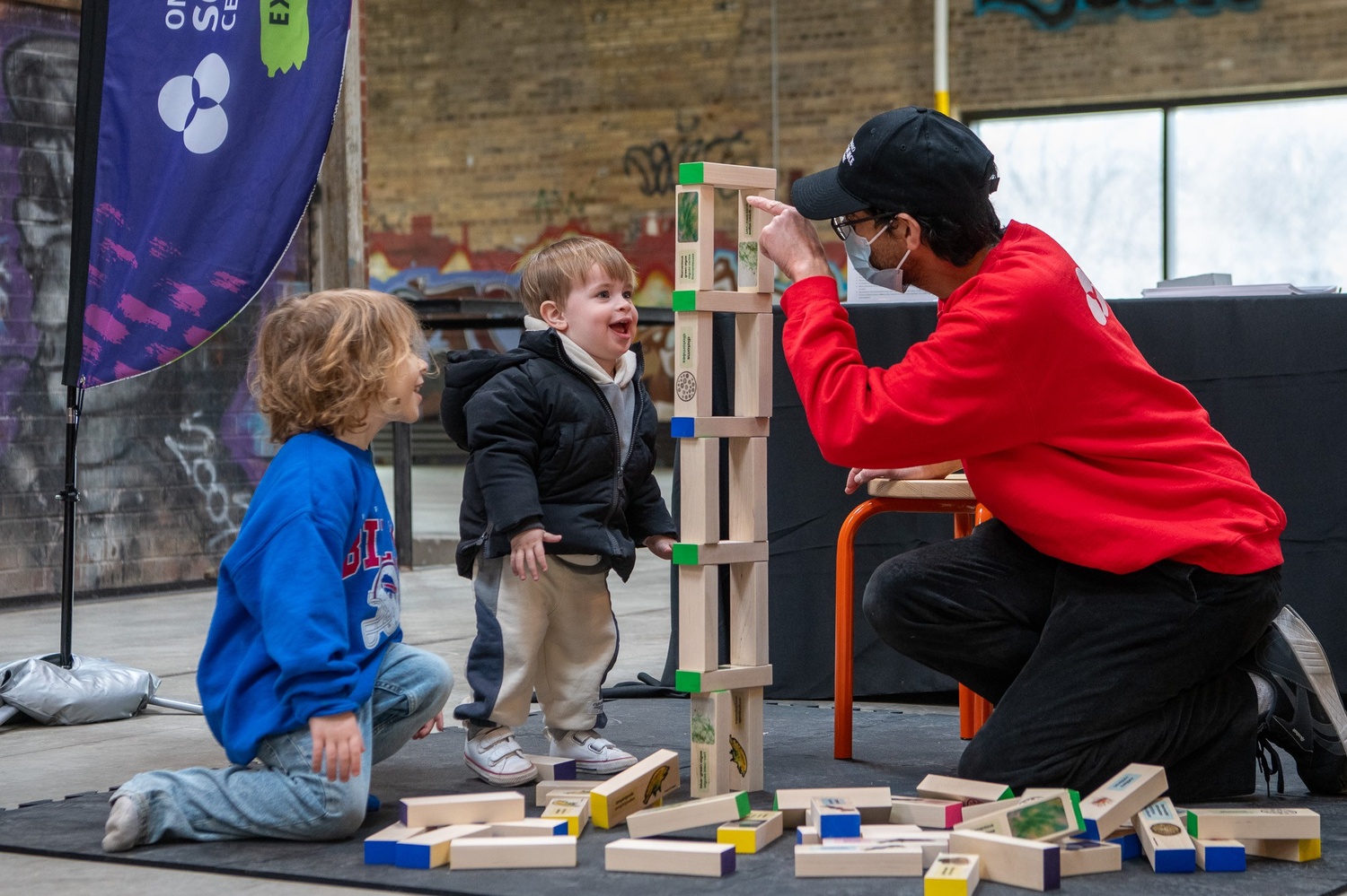 De jeunes enfants jouent à un jeu de blocs Jenga éducatifs avec un scientifique.