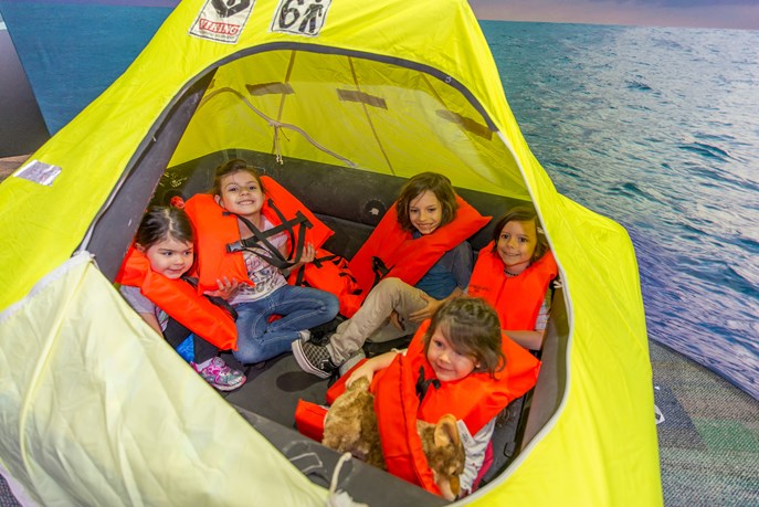 5 enfants en gilets de sauvetage assis dans un radeau gonflable