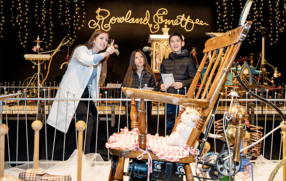 Un membre du personnel du Centre des sciences de l'Ontario et deux enfants observent une machine Emett's.