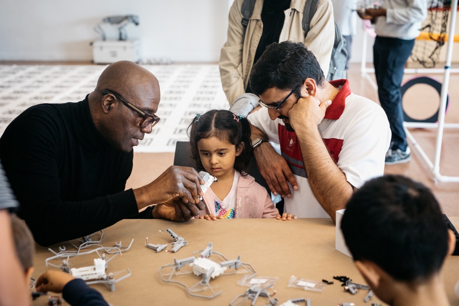 [A girl and her father checking out a drone robotics toy under professional supervision.][Une fille et son père examinent un jouet robotique drone sous la supervision d'un professionnel.]