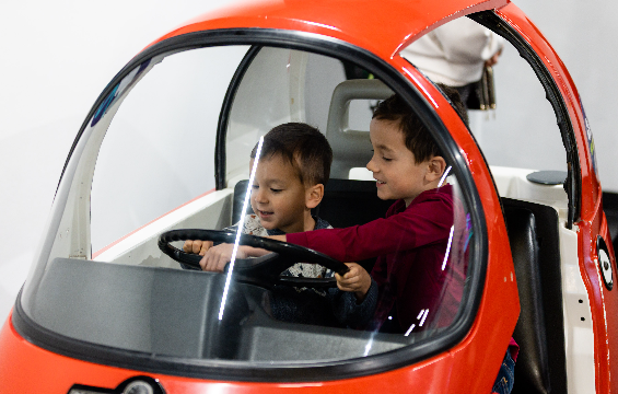 Deux garçons jouent à l'intérieur de la voiture miniature.