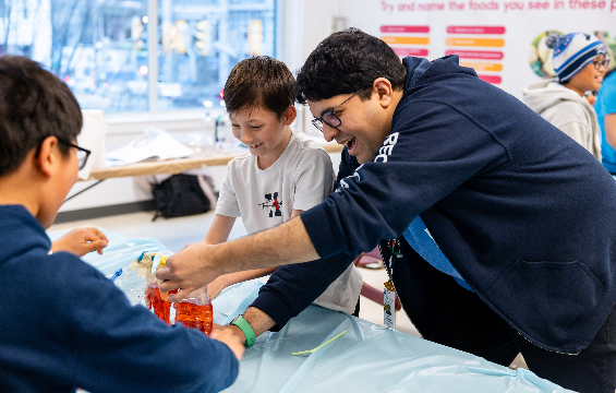 [Kids and research programmer performing a chemistry experiment.][Des enfants et un programmeur de recherche réalisent une expérience de chimie.]