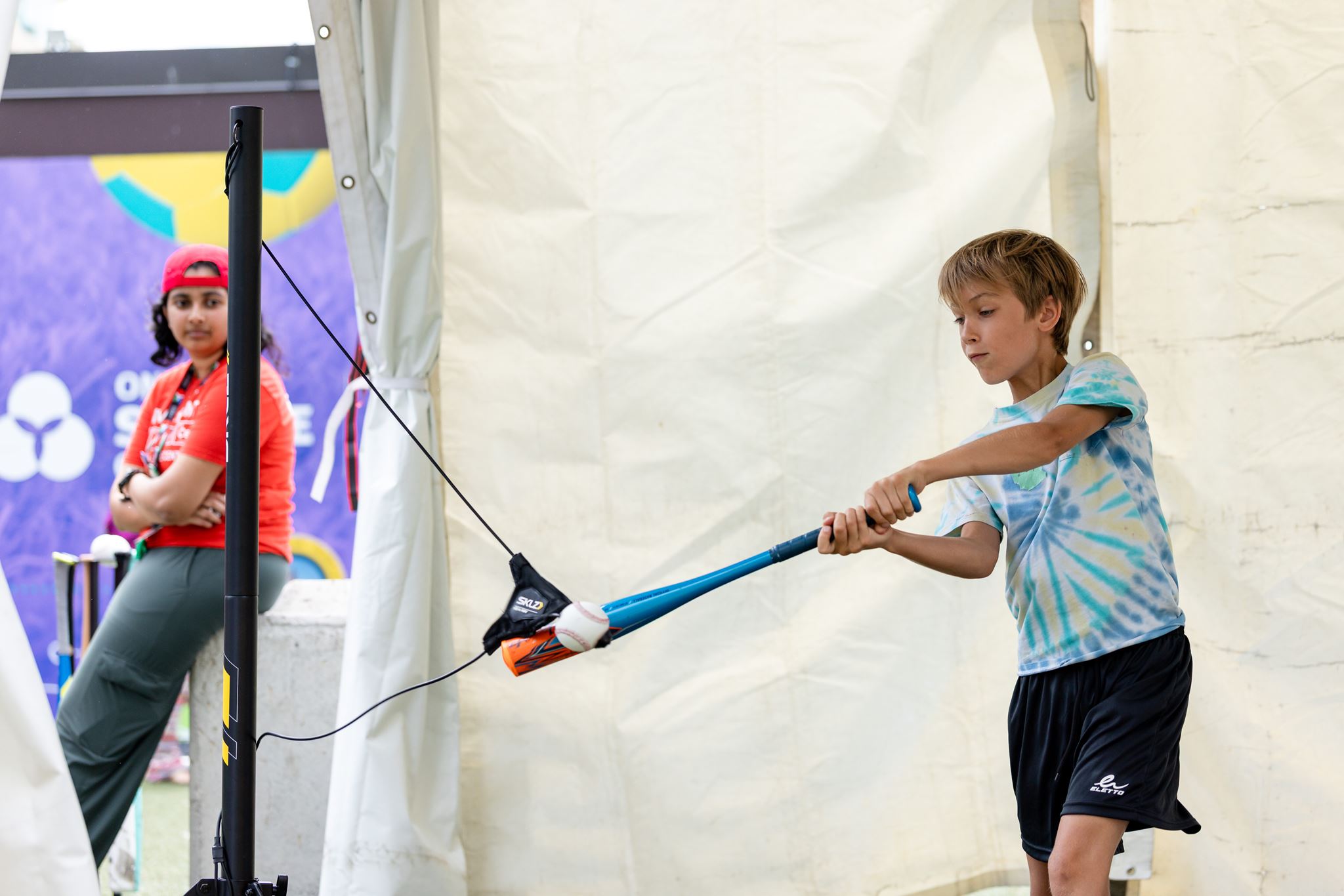 [A boy hitting the baseball with a bat.][Un garçon frappe la balle de baseball avec une batte.]