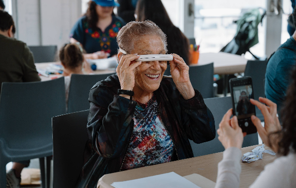 Quelqu'un prend en photo une femme tenant des lunettes de soleil devant son visage.
