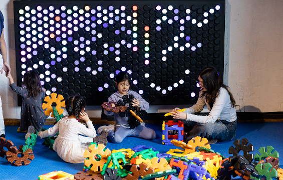 Un groupe d'enfants et leurs accompagnateurs jouent avec des blocs dans l'espace KidSpark.