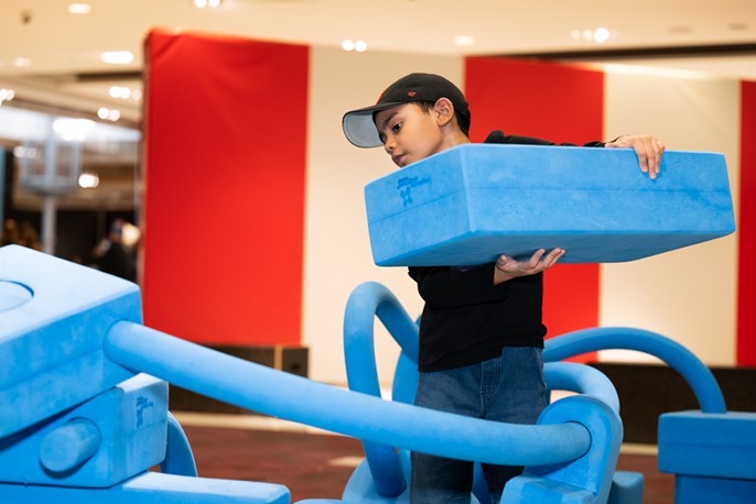 [A boy plays in imagination playground.]Un garçon porte un gros bloc du terrain de jeu imagination playground.]