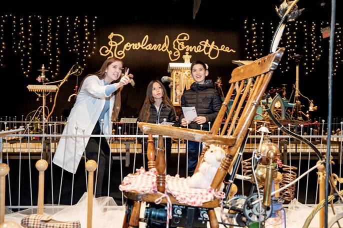 [Ontario Science Centre Staff Member and two kids look at an Emett's Machine.][Un membre du personnel du Centre des sciences de l'Ontario et deux enfants observent une machine Emett's.]