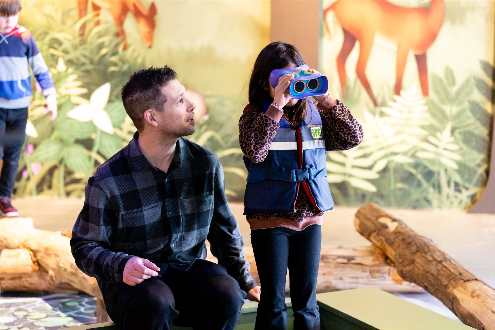 [A girl glancing through a binocular and her father instructing her.][Une fille qui regarde à travers des jumelles et son père qui lui donne des indications.]
