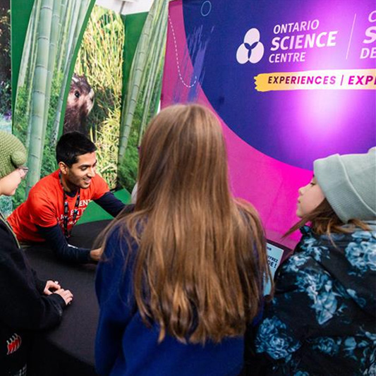 Un membre du personnel d'un centre scientifique s'adresse à un groupe d'enfants.